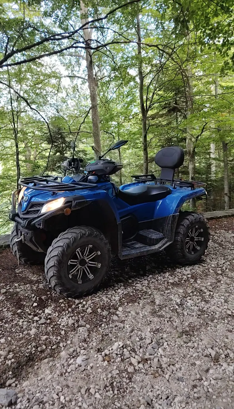 ATV CFMOTO albastru în pădure, model pentru închiriere Sinaia