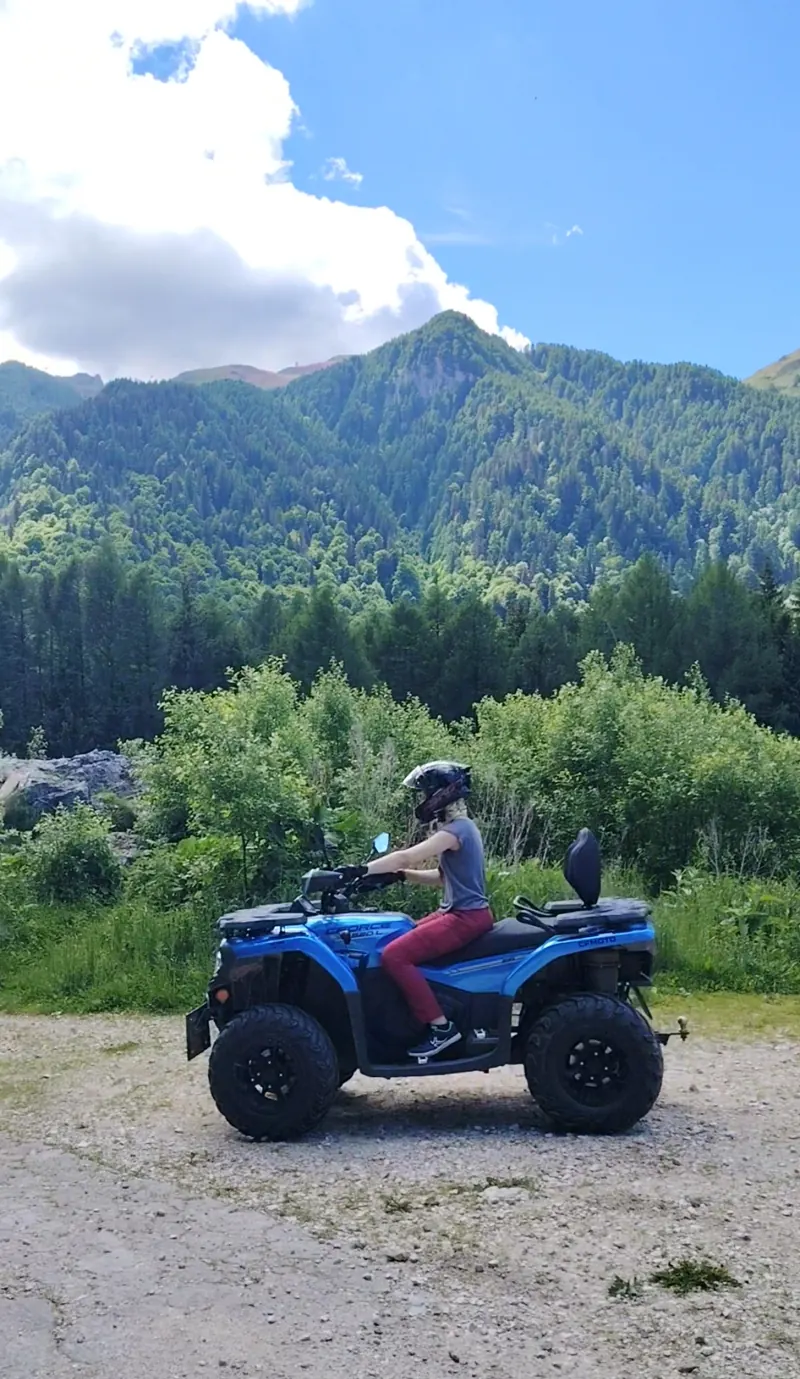 ATV CFMOTO albastru cu turist și panoramă montană pe traseul Stâna Regală