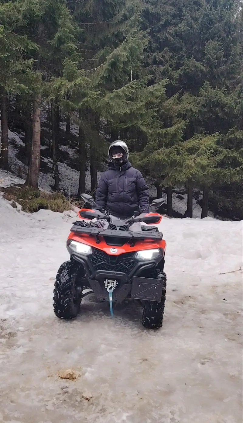 Orange CFMOTO ATV in winter snow on the Cota 1400 trail, Bucegi Mountains Sinaia