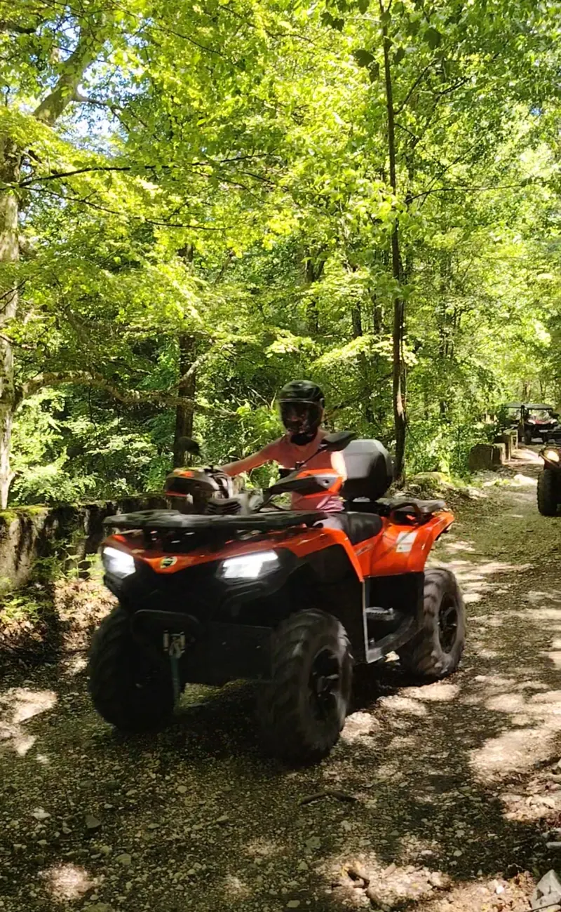 Orange ATV with a tourist on the Forest Road, green forest Sinaia